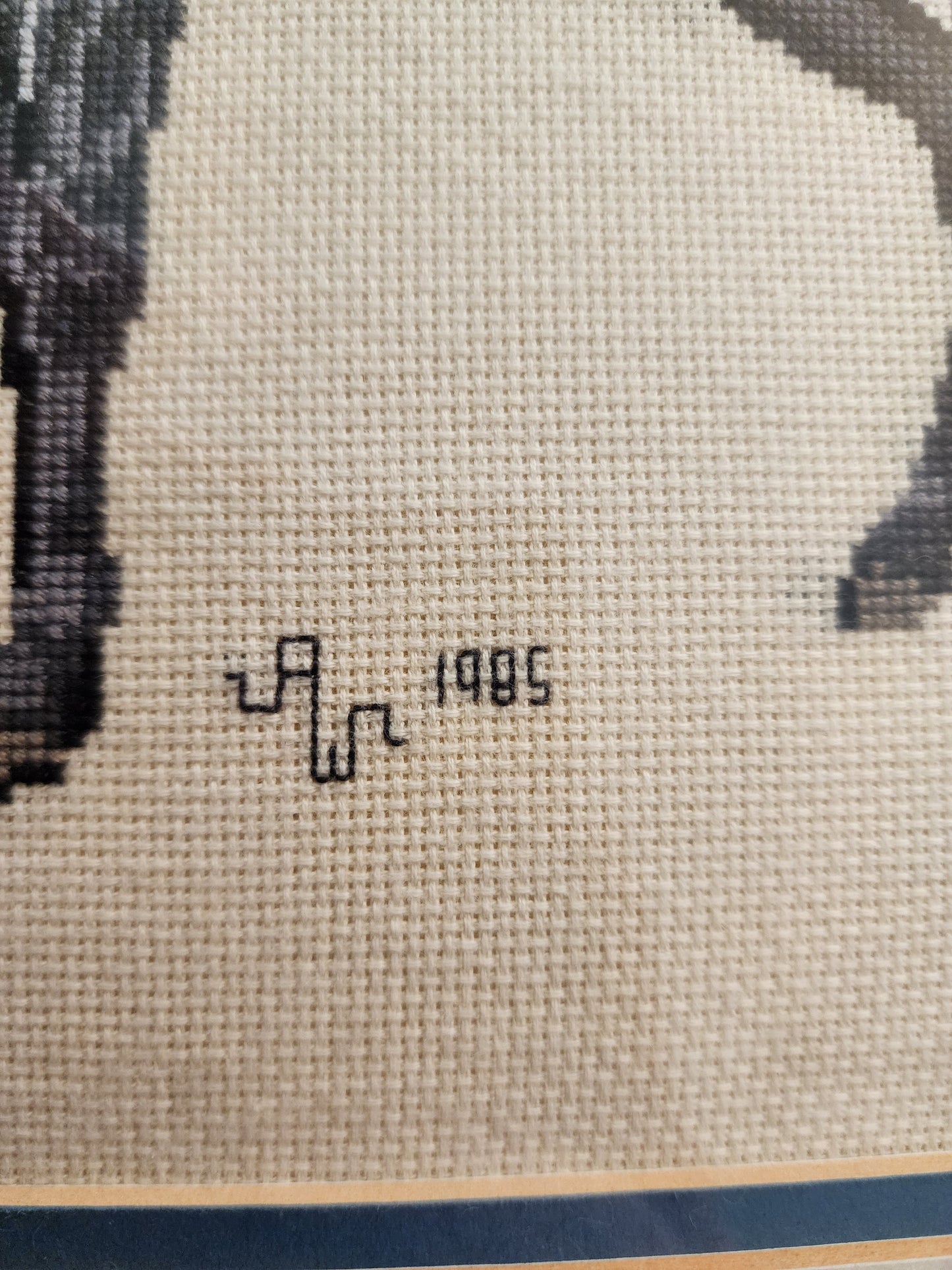 Charming framed needlepoint (or cross-stitch) artwork capturing a classic equestrian scene, signed and dated 1985.